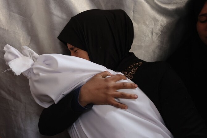 A Palestinian woman mourns as she holds the body of a toddler killed in an Israeli strike. (AFP)