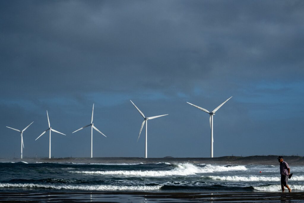 This picture taken on August 9, 2023 shows a man walking on Nikkawahama beach in front of wind turbines in Kamisu, Ibaraki prefecture. (AFP)
