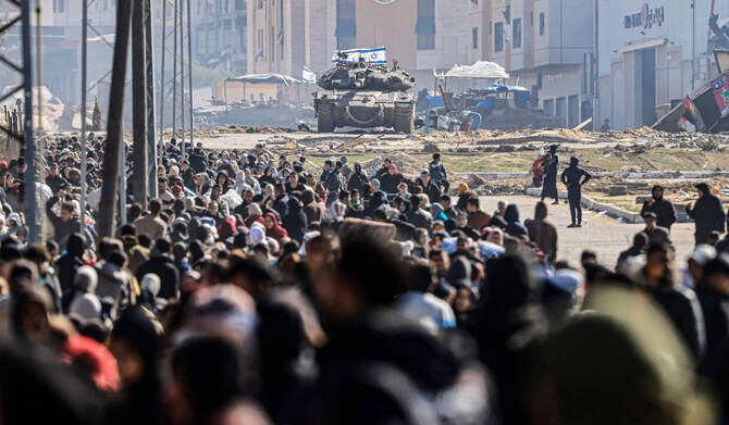 An Israeli tank and other military vehicles guard a position as Palestinians flee Khan Yunis, in the southern Gaza Strip, on January 26, 2024, amid ongoing battles between Israel and the Palestinian militant group Hamas. (AFP)