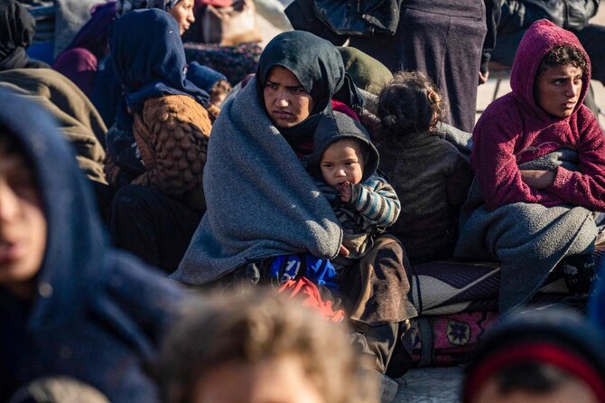A Syrian Kurdish woman and her child waits with others upon their arrival in Tabqa, on the western outskirts of Raqa, after fleeing fighting north of Aleppo. (AFP)
