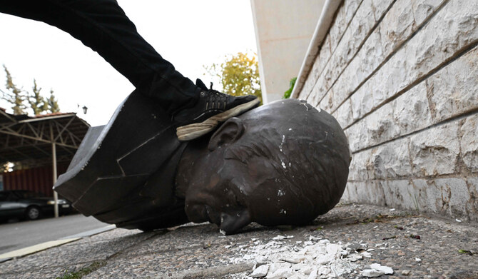 An anti-government fighter steps on the head of a statue of late Syrian president Hafez al-Assad that was brought down outside the Defence Ministry's military security headquarters in the Damascus district of Kafr Sousa on December 9, 2024. (AFP)