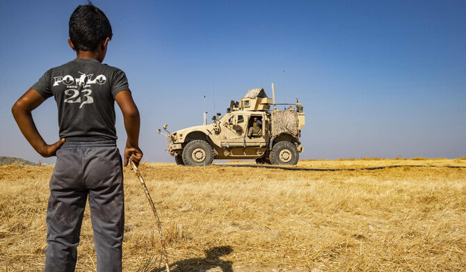 A Syrian boy watches as US military vehicle takes part in joint patrol with Turkish forces in the Syrian village of al-Hashisha on the outskirts of Tal Abyad town along the border with Turkey, on October 4, 2019. (AFP)