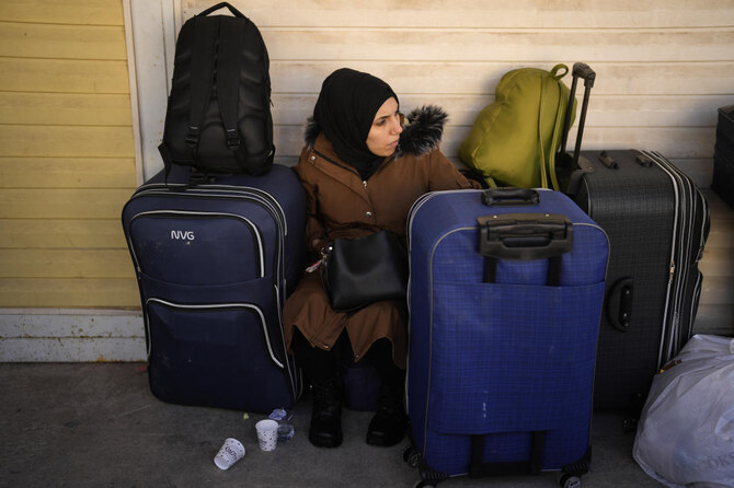 A Syrian woman rests next to her belongings as she waits to cross into Syria from Turkey at the Oncupinar border gate, near the town of Kilis, southern Turkey, Tuesday, Dec. 17, 2024. (AP Photo/Khalil Hamra)