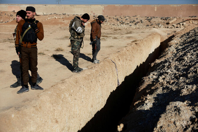 Fighters of the ruling Syrian body inspect the site of a mass grave in Najha. (Reuters)