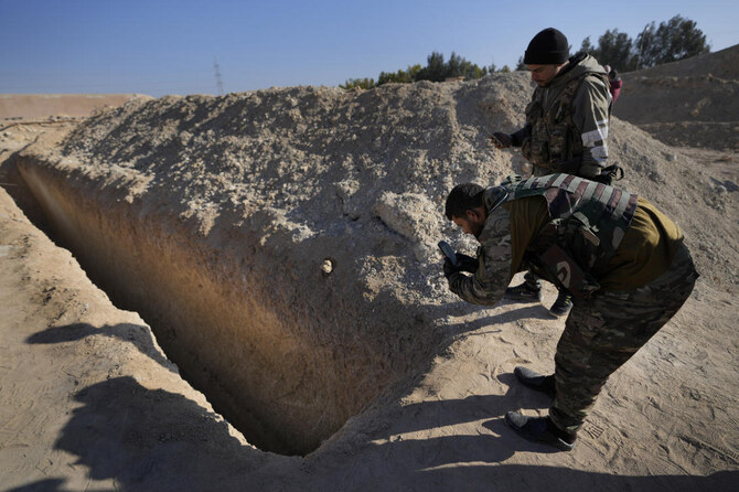 Syrian fighters observe a location identified as a mass grave for detainees killed under the rule of Bashar Assad in Najha, south of Damascusn Najha, south of Damascus. (AP)