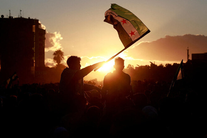 Person holds up the flag adopted by the new Syrian rulers, as people celebrate after fighters of the ruling Syrian body ousted Bashar al-Assad, in the Damascus old city, Syria. (File/Reuters)