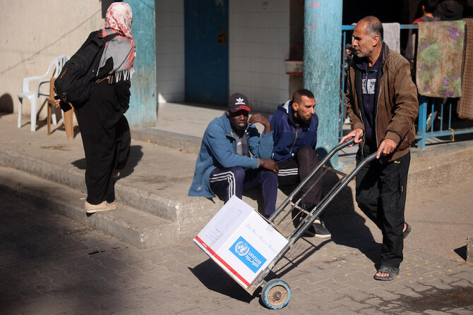 A man transports a box of relief food delivered by the UN agency supporting Palestinian refugees at Bureij camp in the Gaza Strip on Dec. 5, 2024. (AFP)