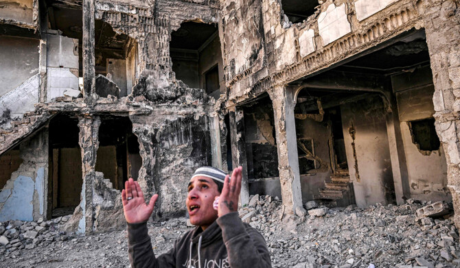 Mahmud Khaled Ajaj, 30, reacts while standing before a destroyed apartment building in the Yarmuk camp for Palestinian refugees south of Damascus on December 19, 2024. (AFP)