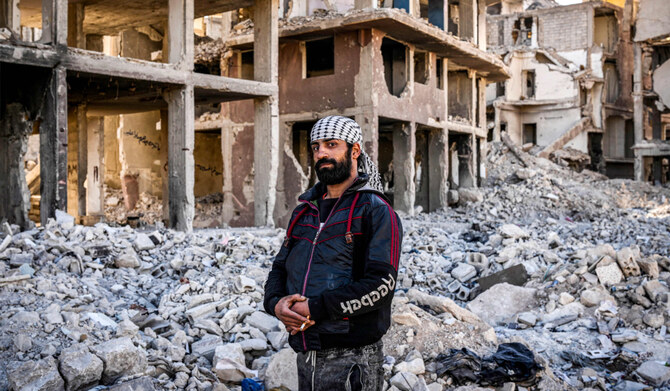 Haitham Hassan al-Nada, 28, poses before a destroyed apartment building in the Yarmuk camp for Palestinian refugees south of Damascus on December 19, 2024. (AFP)