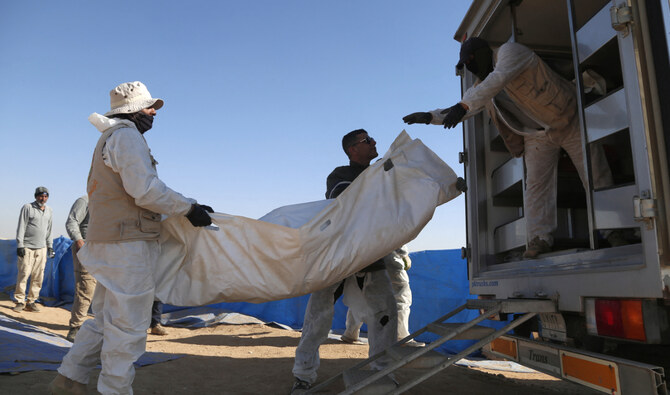Forensic experts load human remains exhumed from a mass grave onto a truck in Tal Al-Shaikhia in the Muthanna province in southern Iraq on December 25, 2024. (AFP)