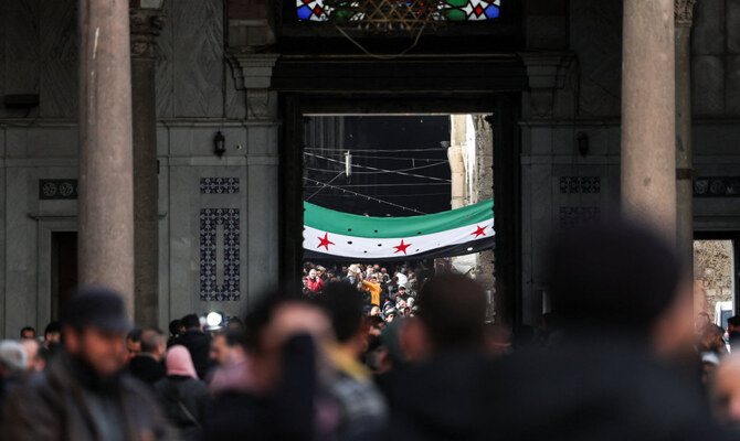 People walk as a flag adopted by the new Syrian rulers is seen, in the Umayyad Mosque, after Syria's Bashar al-Assad was ousted, in Damascus, Syria, December 27, 2024. (Reuters)