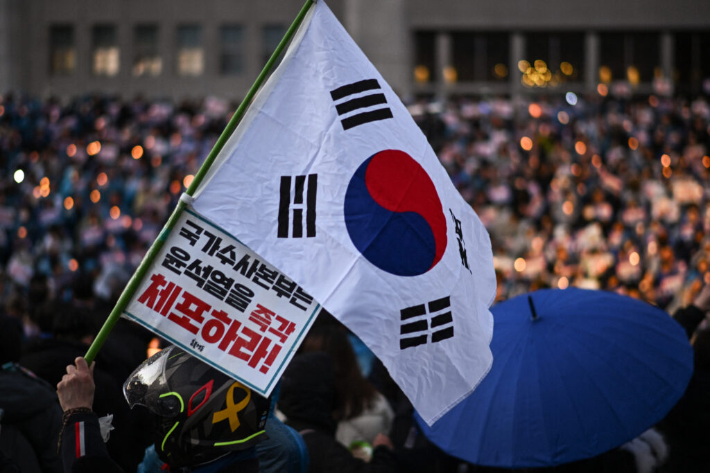 A protester holds the South Korea flag during a candlelight rally calling for the ouster of South Korea President Yoon Suk Yeol at the National Assembly in Seoul on December 5, 2024. (AFP)