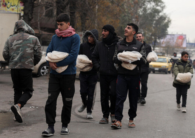 People walk with food in plastic bags, after rebels seized the capital and ousted Syria's Bashar Assad, in Damascus on Thursday. (Reuters)