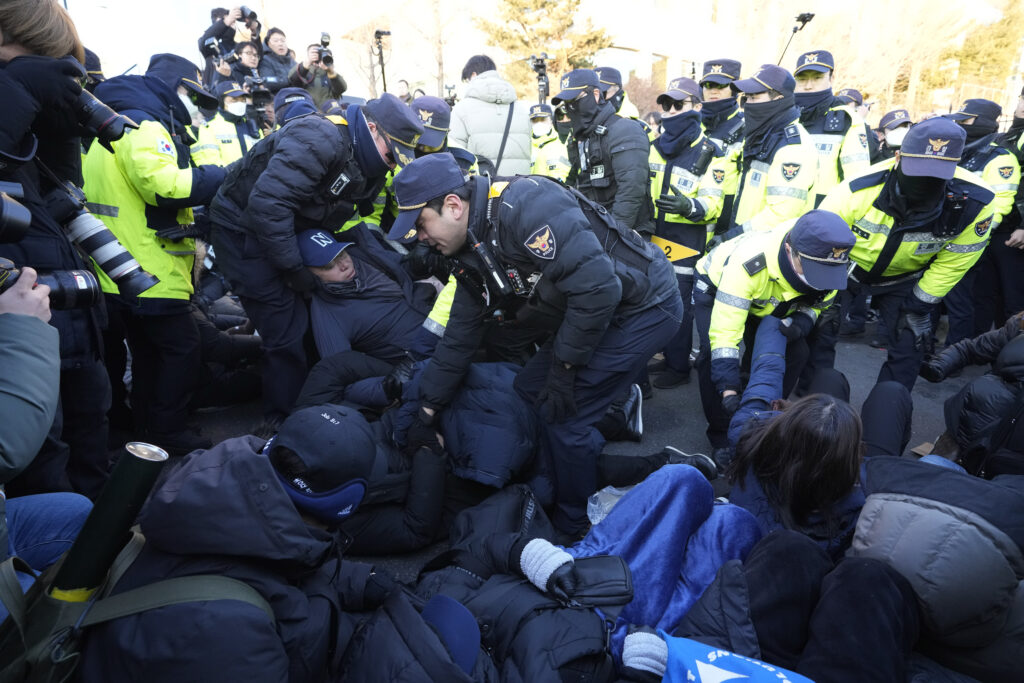 Police officers drag away supporters of impeached South Korean President Yoon Suk Yeol as Yoon faces potential arrest after a court on Tuesday approved a warrant for his arrest, near the presidential residence in Seoul, South Korea, Thursday, Jan. 2, 2025. (AP Photo/Ahn Young-joon)
