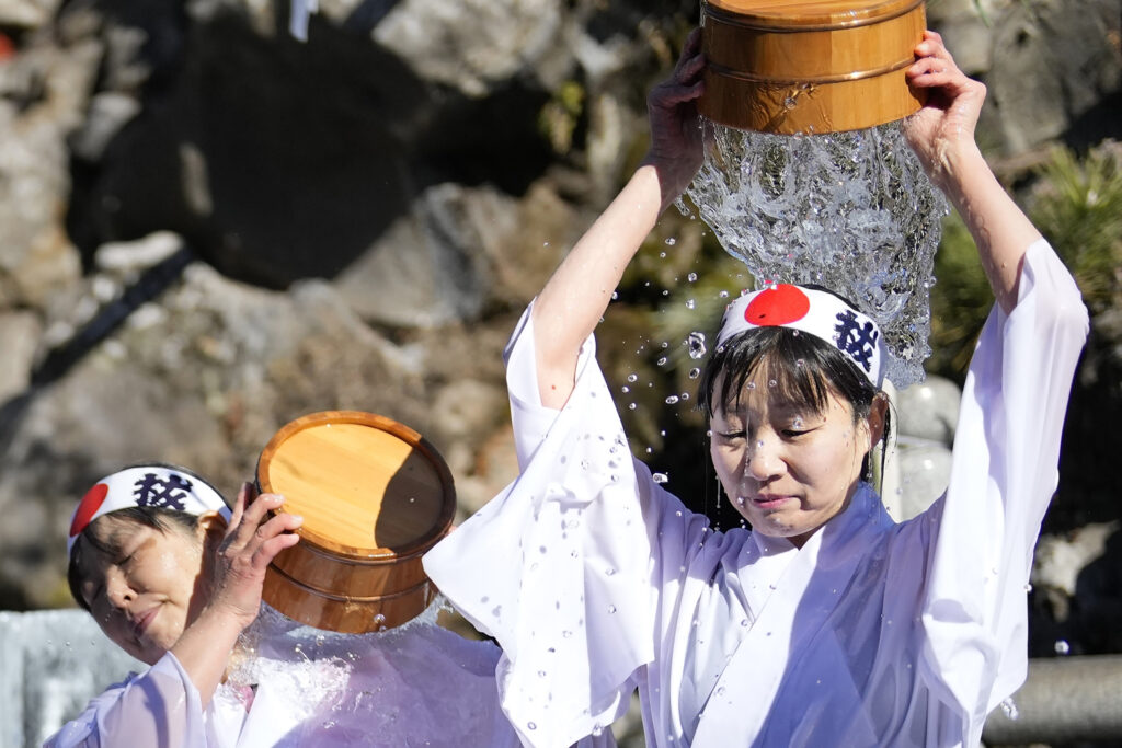 About 40 participants jogged around the shrine and did some physical exercises to warm up before entering a pool of knee-high water chilled further with big chunks of ice. (AP Photo/Eugene Hoshiko)