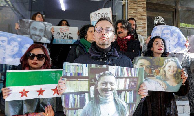 Protesters gather for a vigil seeking information about Syrian activists Samira Khalil, Razan Zeitouneh, Wael Hamada, and Nazem al-Hammadi who were abducted by unidentified assailants in December 2013, in Douma on the eastern outskirts of Damascus on January 1, 2025. (AFP)