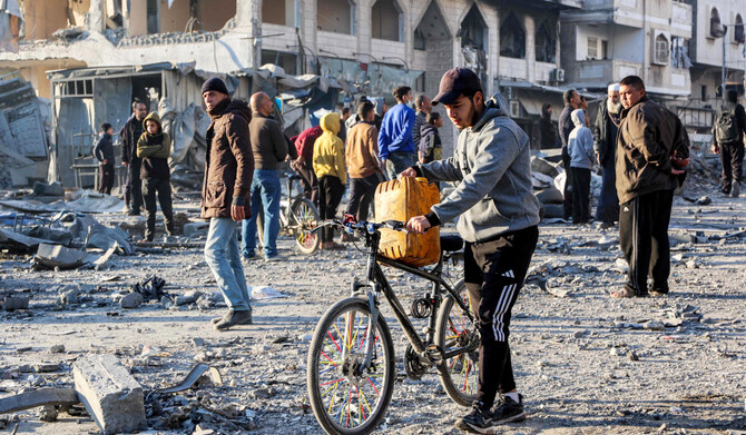 A man walks with a jerrycan balanced on a bicycle through debris at the site of Israeli bombardment on a residential block in Jalaa Street in Gaza City on January 14, 2025 amid the ongoing war in the Palestinian territory between Israel and Hamas. (AFP)