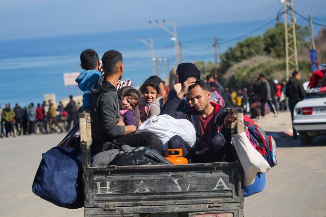 Displaced Palestinians sit in the back of a vehicle near a roadblock on Salah Al-Din Street in Nuseirat on Jan. 25, 2025, while waiting to return to their homes in the northern part of the Gaza Strip. (AFP)