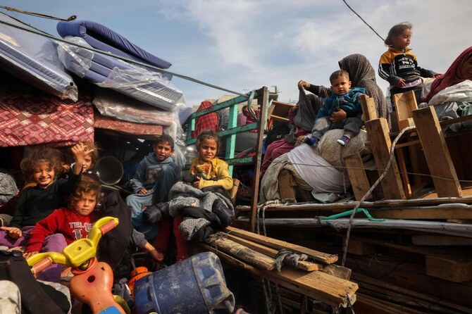 Displaced Palestinian children sit on the back of trucks waiting along Salah Al-Din road in Nuseirat as people make their way to the northern part of the Gaza strip on Jan. 28, 2025. (AFP)