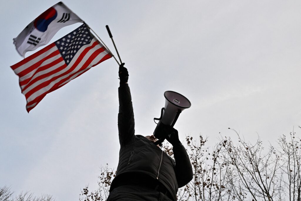 A pro-Yoon supporter waves A US and a South Korean flags on a road outside the Seoul Western District Court in Seoul on January 18, 2025. (AFP)
