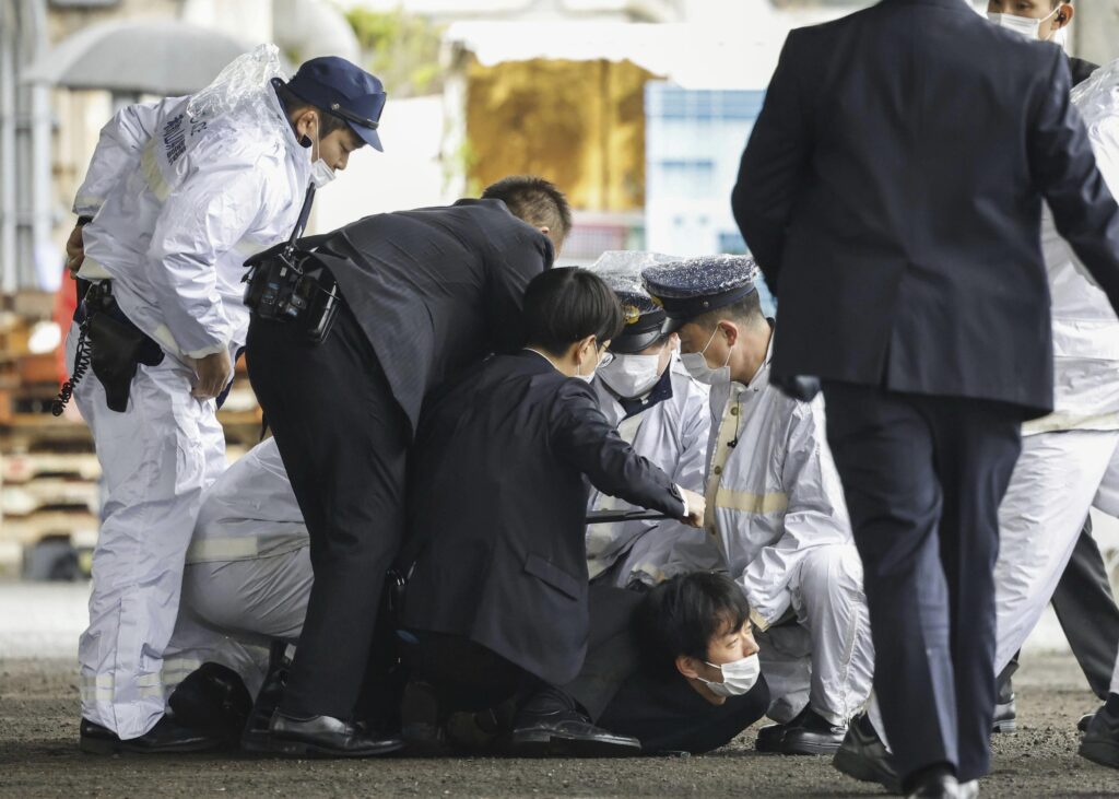 A suspect, center on the ground, is caught by police after he allegedly threw