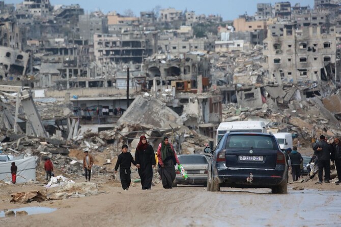 Displaced Palestinians walk through a muddy road amid the destruction in Jabalia in the northern Gaza Strip on February 6, 2025. (AFP)