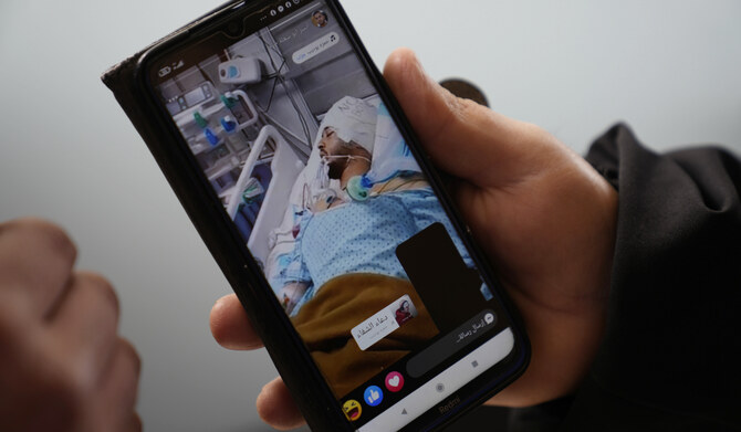 Mohammed Shula displays a picture of his hospitalized son, Yazan, while inside a relative's house where he and his wife have taken refuge at the West Bank village of Kafr al-Labad, Monday, Feb. 10, 2025. (AP)