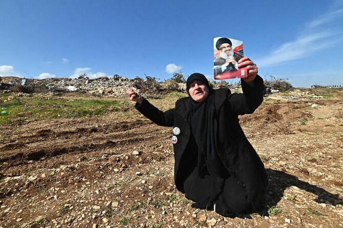 A woman holds a portrait of slain Hezbollah leader Hassan Nasrallah as residents return accompanied by the Lebanese army to the devastated southern Lebanese village of Maroun el Ras, on February 18, 2025. (AFP)