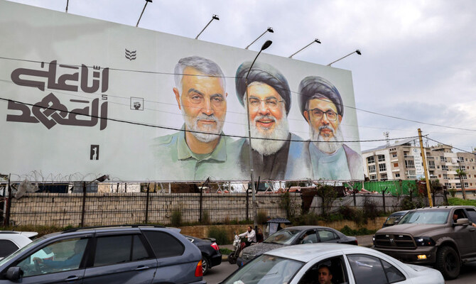 Traffic moves beneath a banner depicting the slain leader of the Lebanese Shiite Islamist movement Hezbollah Hassan Nasrallah (C) and his deputy Hashem Safieddine (C-R) as well as that of slain Iranian General Qassem Soleimani on Beirut Airport Road, in Beirut on February 19, 2025. (AFP)