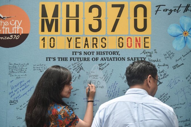 A woman writes a message during an event held by relatives of the passengers and supporters to mark the 10th year since the Malaysia Airlines flight MH370 carrying 239 people disappeared from radar screens on March 8, 2014 while en route from Kuala Lumpur to Beijing, in Subang Jaya on March 3, 2024. (AFP)
