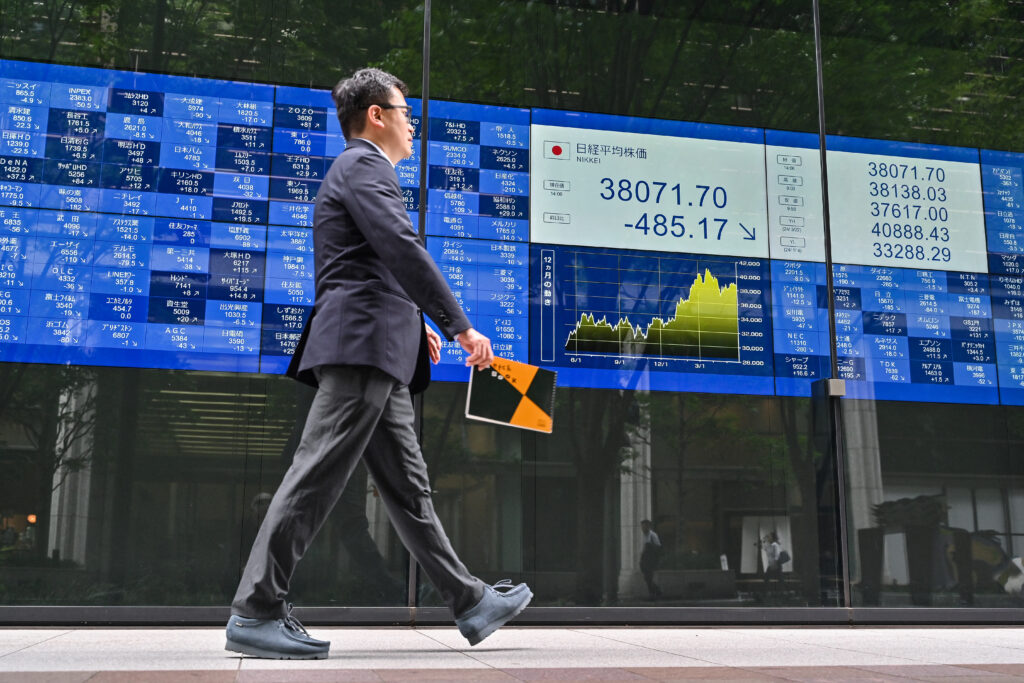A man walks past an electronic board showing the numbers during afternoon trade on the Tokyo Stock Exchange in central Tokyo on May 30, 2024. (AFP)