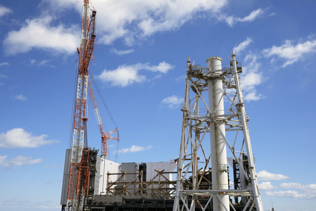 The damaged Unit 1 reactor, back, and the exhaust stack shared by the Unit 1 and 2 reactors are seen at the Fukushima Daiichi nuclear power plant, operated by Tokyo Electric Power Company Holdings (TEPCO), in Okuma town, northeastern Japan on Monday Feb. 20, 2025. (AP Photo)