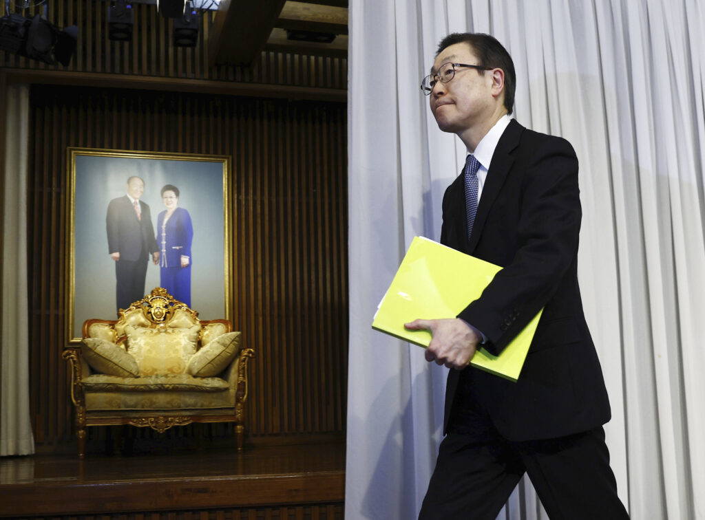 Tomihiro Tanaka, president of the Unification Church's Japanese branch, leaves a press conference at its headquarters after the church in Japan was ordered dissolved by a court in Tokyo, Tuesday, March 25, 2025. The portrait shows the church's founder late Rev. Sun Myung Moon and his wife Hak Ja Han. (Kyodo News via AP)