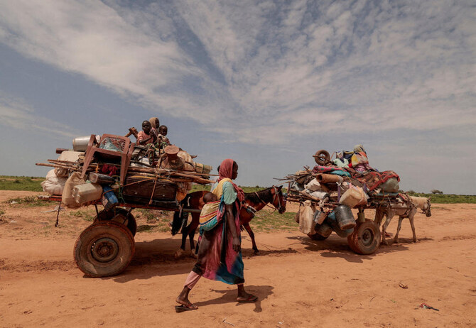 FILE PHOTO: A Sudanese woman, who fled the conflict in Murnei in Sudan's Darfur region, walks beside carts carrying her family belongings upon crossing the border between Sudan and Chad in Adre, Chad August 2, 2023. (Reuters)