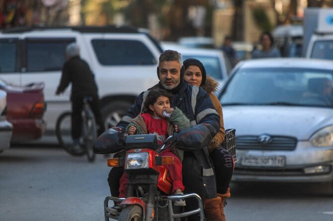 A family of three rides on a motorcycle in the Druze-majority Jaramana city in the Damascus countryside, March 2, 2025. (AFP)