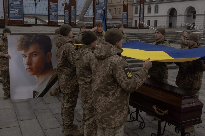 Ukrainian soldiers hold a national flag over a serviceman who was killed in action during his funeral ceremony in Kyiv on March 2, 2025. (AFP)