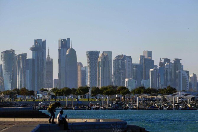 Men sit at the Doha Corniche backdropped by high buildings in Doha on March 3, 2025, during Ramadan. (AFP)