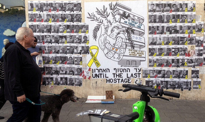 People walk next to a graffiti supporting the release of all hostages who have been held in Gaza since the deadly October 7, 2023 attack, in Tel Aviv, Israel, February 18, 2025. (Reuters)