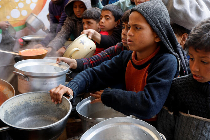 Palestinian children wait to receive food cooked by a charity kitchen, during Ramadan, in Khan Younis, in the southern Gaza Strip, March 9, 2025. (Reuters)