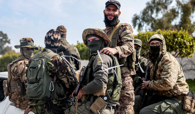 Security forces loyal to the interim Syrian government ride in the back of a vehicle moving along a road in Syria's western city of Latakia on March 9, 2025. (AFP)