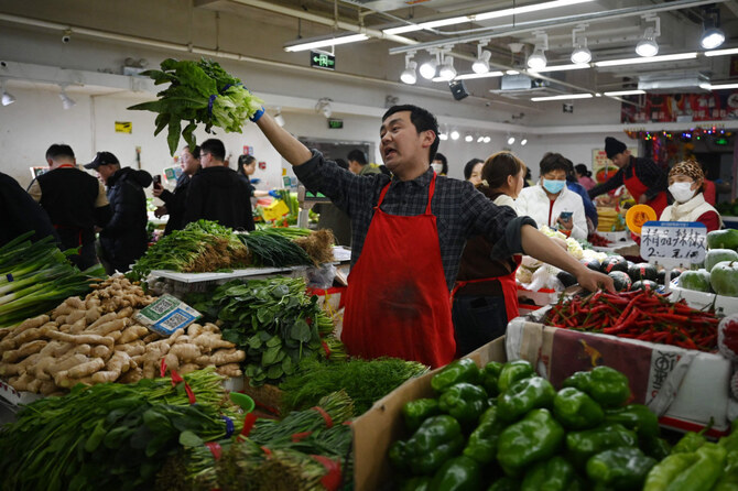A vendor shouts out his price for lettuce in a market in Beijing on March 9, 2025, as China's trade war with the US escalates, triggered by Trump's tariffs. (AFP)