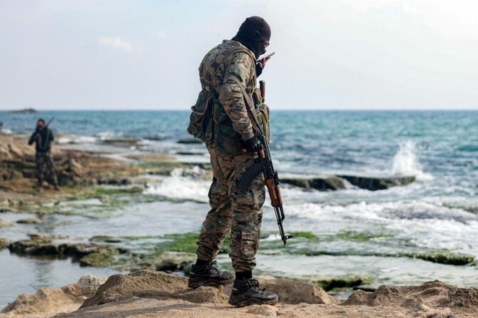 A member of security forces loyal to the interim Syrian government speaks on a cell phone while standing by the Mediterranean sea coast in Latakia. (File/AFP)