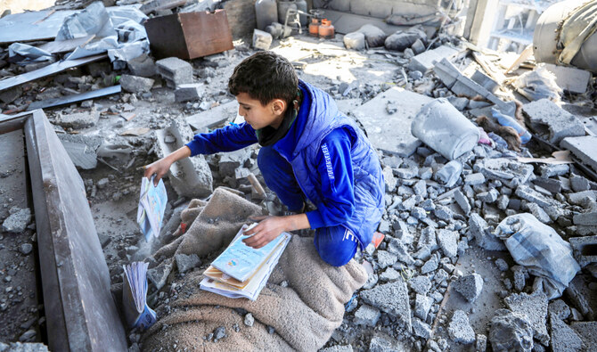 A Palestinian boy collects books at the site of an Israeli strike on a house, in Gaza City, March 24, 2025. (Reuters)