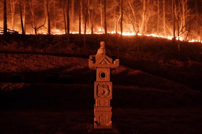 South Korea is battling one of its worst wildfire outbreaks, with multiple raging blazes causing ‘unprecedented damage.’ Above, a wildfire is seen next to a stone lantern of family tomb in Andong on March 26, 2025. (AFP)