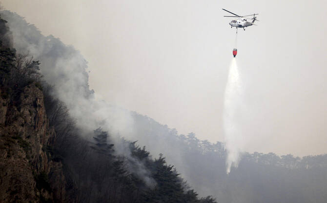 A helicopter tries to extinguish a wildfire at a national park in Cheongsong, South Korea on March 27, 2025. (Newsis via AP)