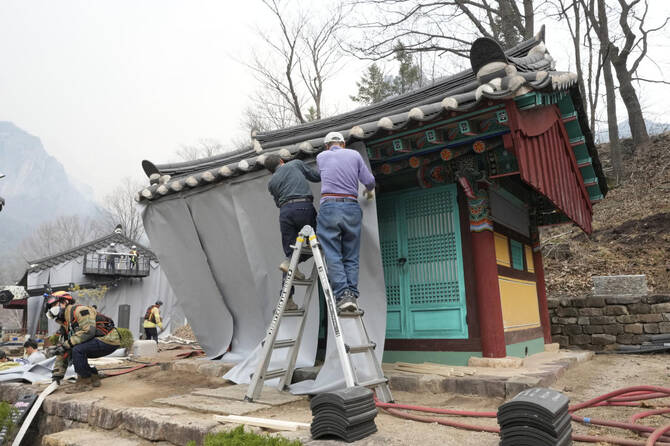 Workers cover temples with fireproof fabric in preparation for a possible approaching wildfire at a temple in Cheongsong, South Korea on March 27, 2025. (AP)