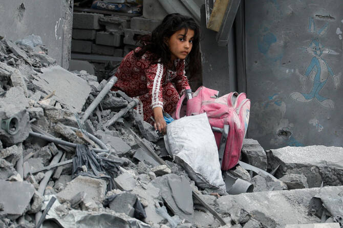 A girl holds a bag as Palestinians inspect the site of an Israeli strike on a house, in Khan Younis in the southern Gaza Strip April 1, 2025. (REUTERS)