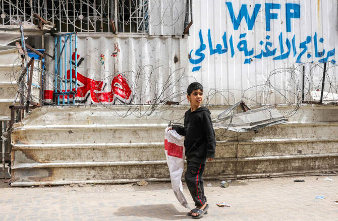 A Palestinian youngster walks with an empty sack past a closed-down bakery that ran out of flour in Gaza City on Tuesday. (AFP)