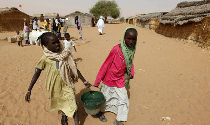 Sudanese refugee girls carry water supplies near a polling station in the refugee camp of Zamzam, on the outskirts of El-Fasher, Darfur, Sudan. (AP/File)