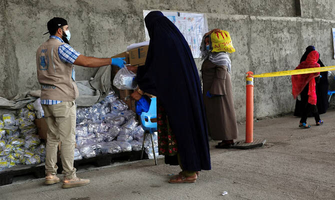 An Afghan woman receives food items for her children at a World Food Program (WFP) distribution centre in Kabul, Afghanistan. (Reuters/File)